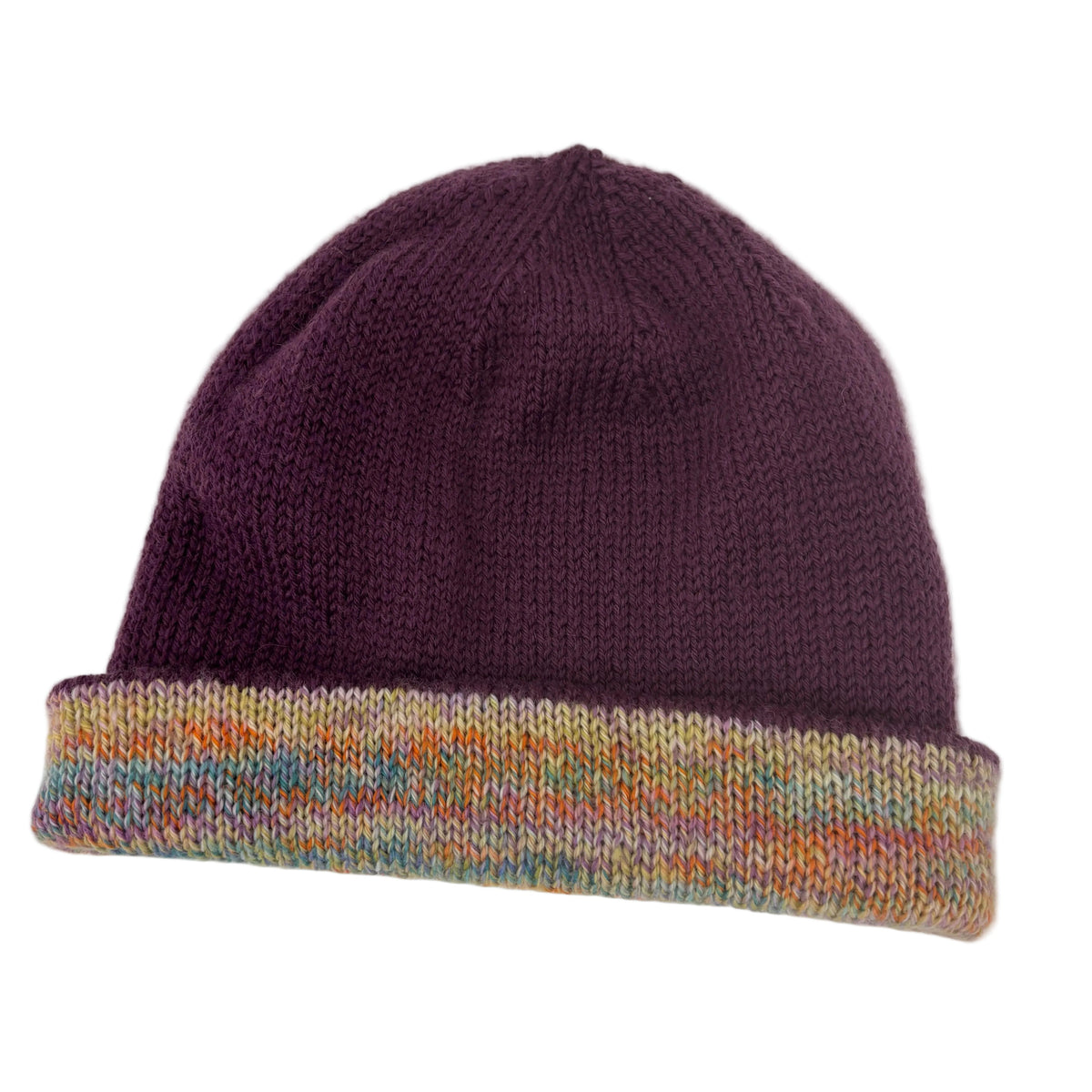 A hand-knit beanie hat featuring a solid deep plum purple crown and a folded cuff with a multicolor variegated knit pattern of orange, blue, yellow, and cream, shown against a plain white background.